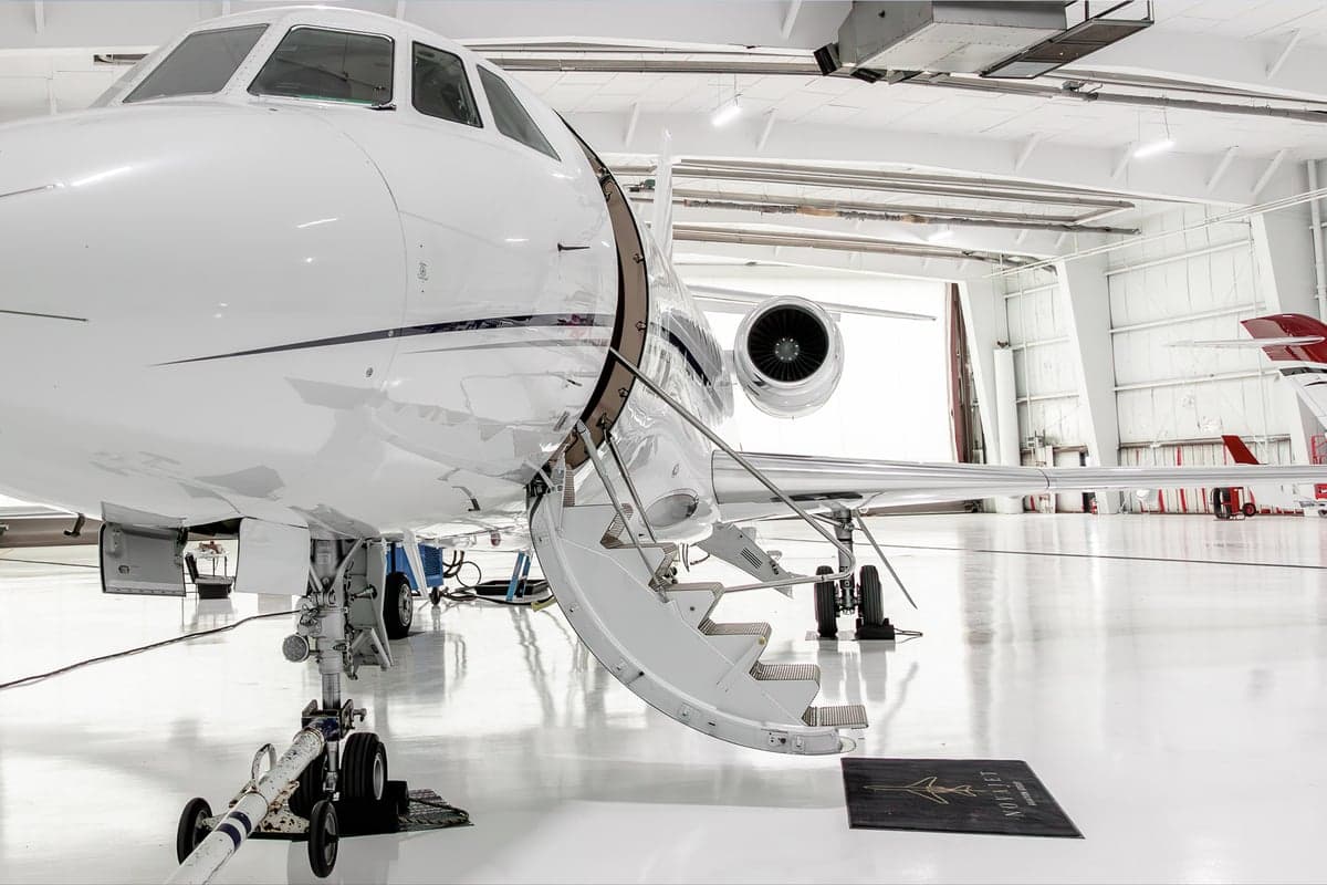 Close-up of the aircraft's entrance with stairs extended, inside a hangar.
