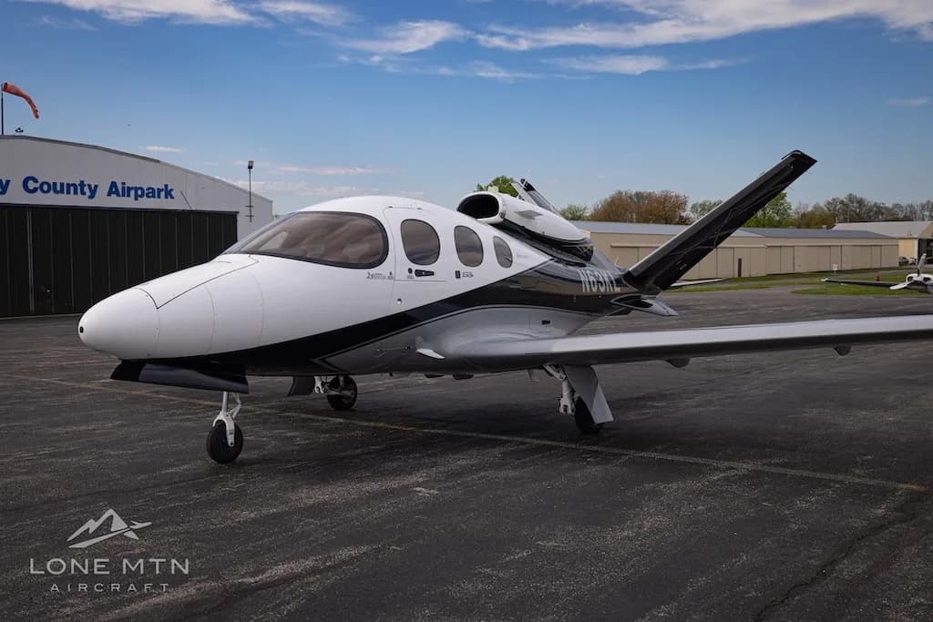 A white and black Cirrus Vision Jet (N63KL) parked on an asphalt apron in front of a hangar labeled "Montgomery County Airpark".