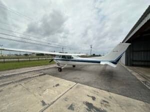 Side view of a Cessna aircraft parked on the tarmac next to a hangar.
