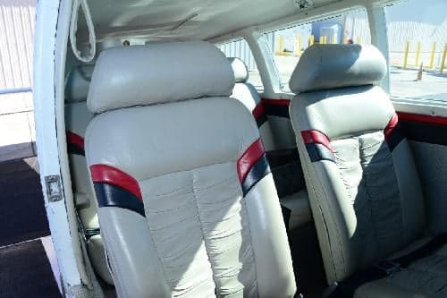 The aircraft's interior features light gray seats with red and black accents.