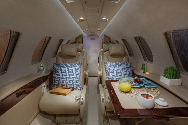 Interior of the Cessna Citation CJ3+ cabin with leather seats and a table set for a meal.