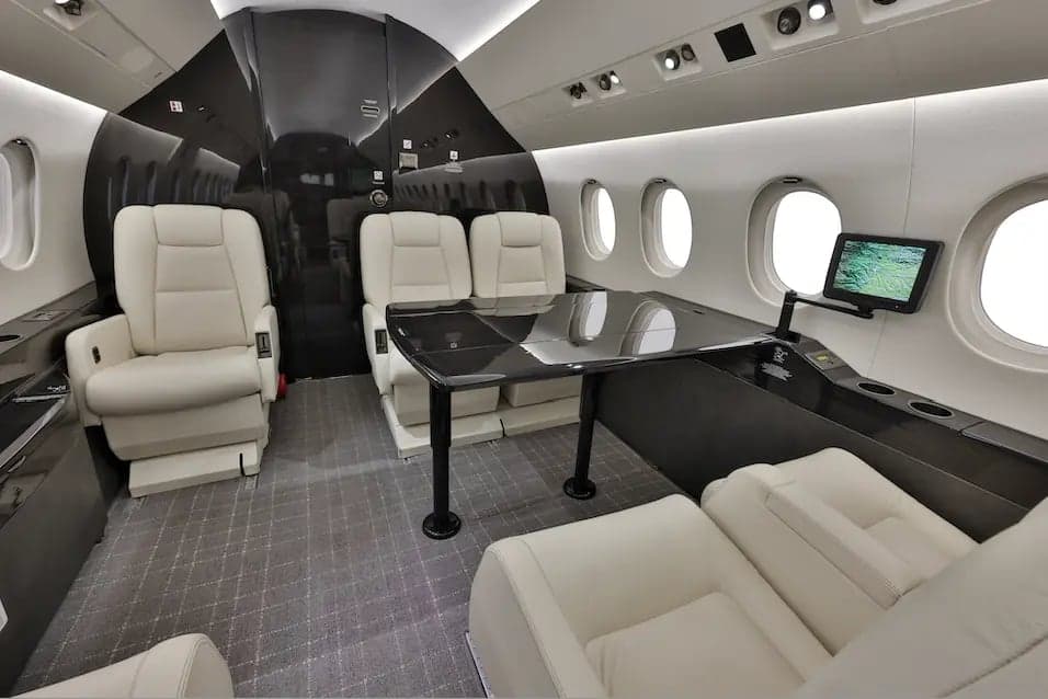Aircraft cabin with cream-colored seats and a black table.