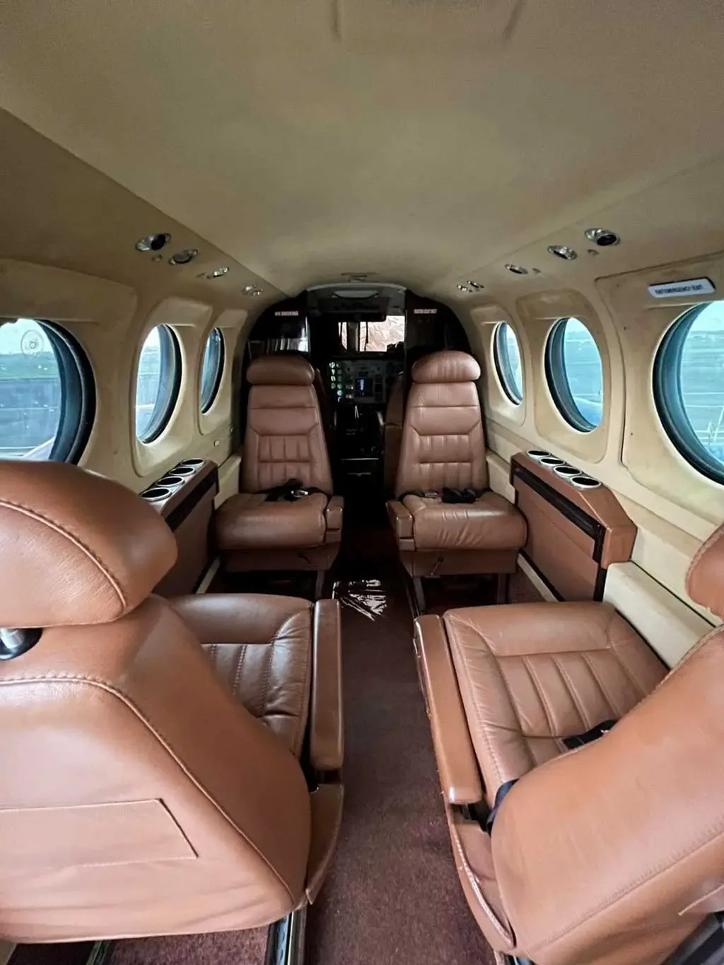 The interior cabin of an aircraft with brown leather seats arranged in a club configuration.