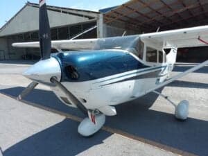 A Cessna aircraft with blue and white paint scheme, parked on the tarmac with the propeller visible.