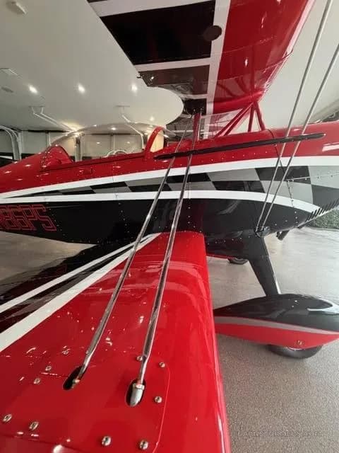 A close-up view of the red and black biplane's lower wing and fuselage, showing the "N86PS" registration.