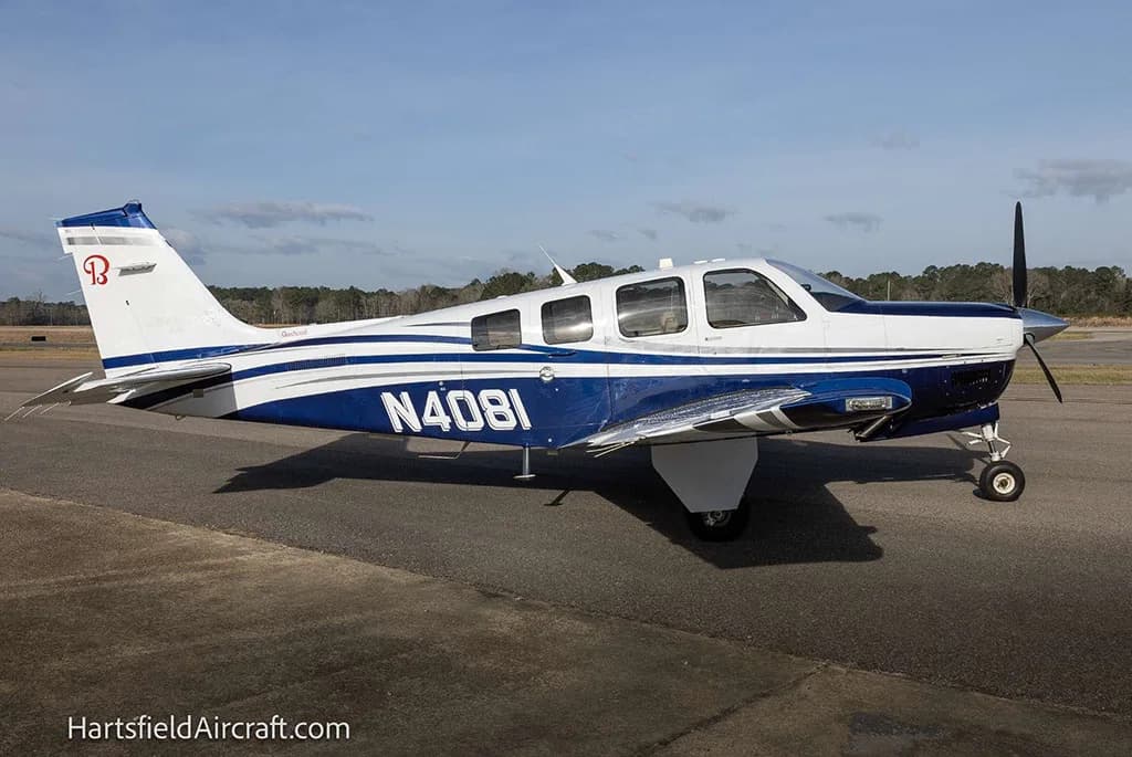 A side view of a white and blue Beechcraft Bonanza N4081 parked on an airfield.