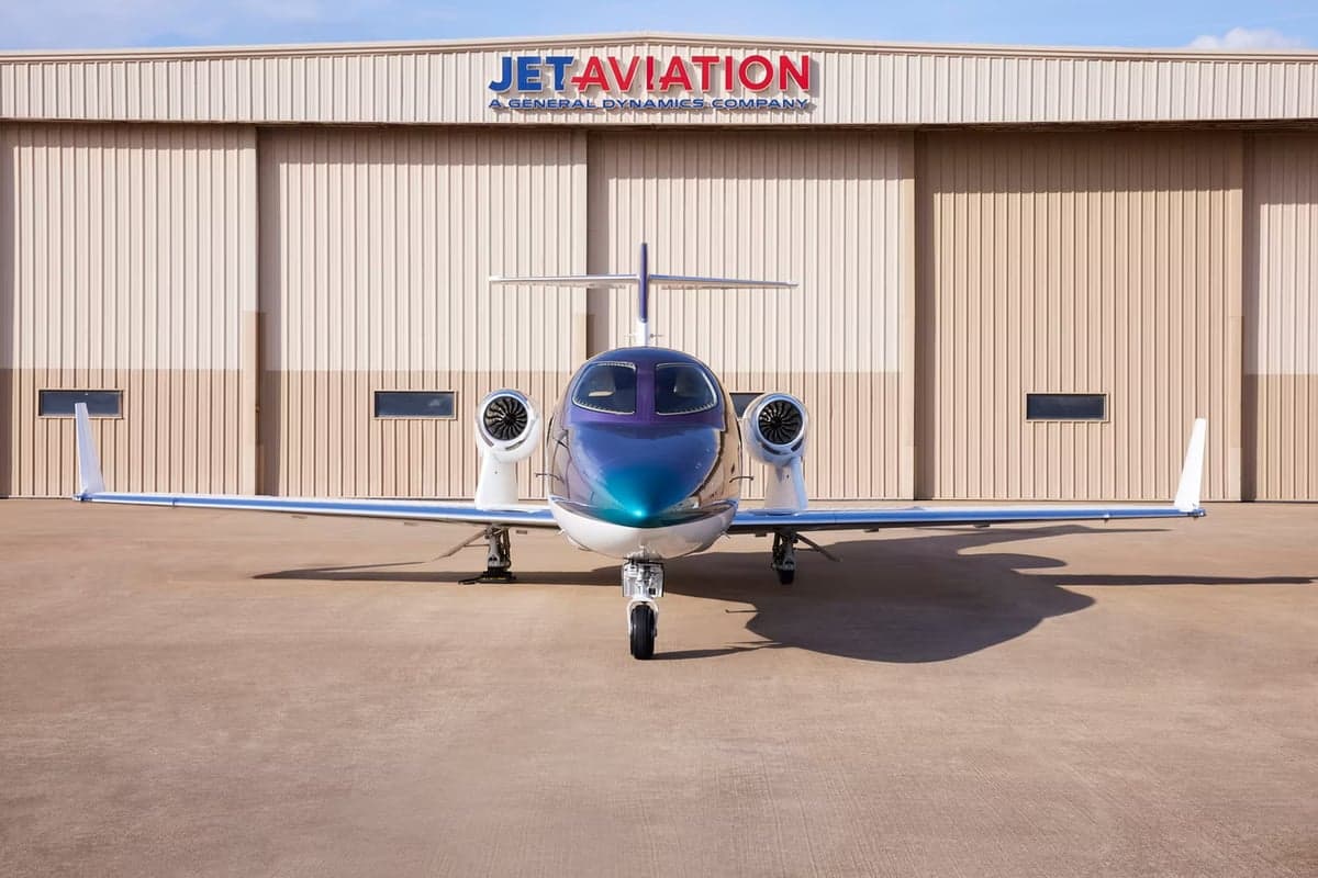 Front view of a HondaJet parked in front of a Jet Aviation hangar.