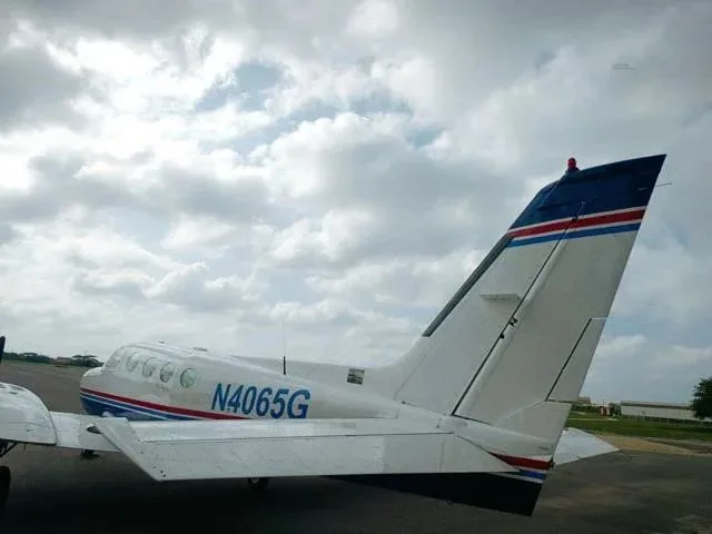 A close-up rear view of the tail and right wing of a white and blue Cessna 340 aircraft.