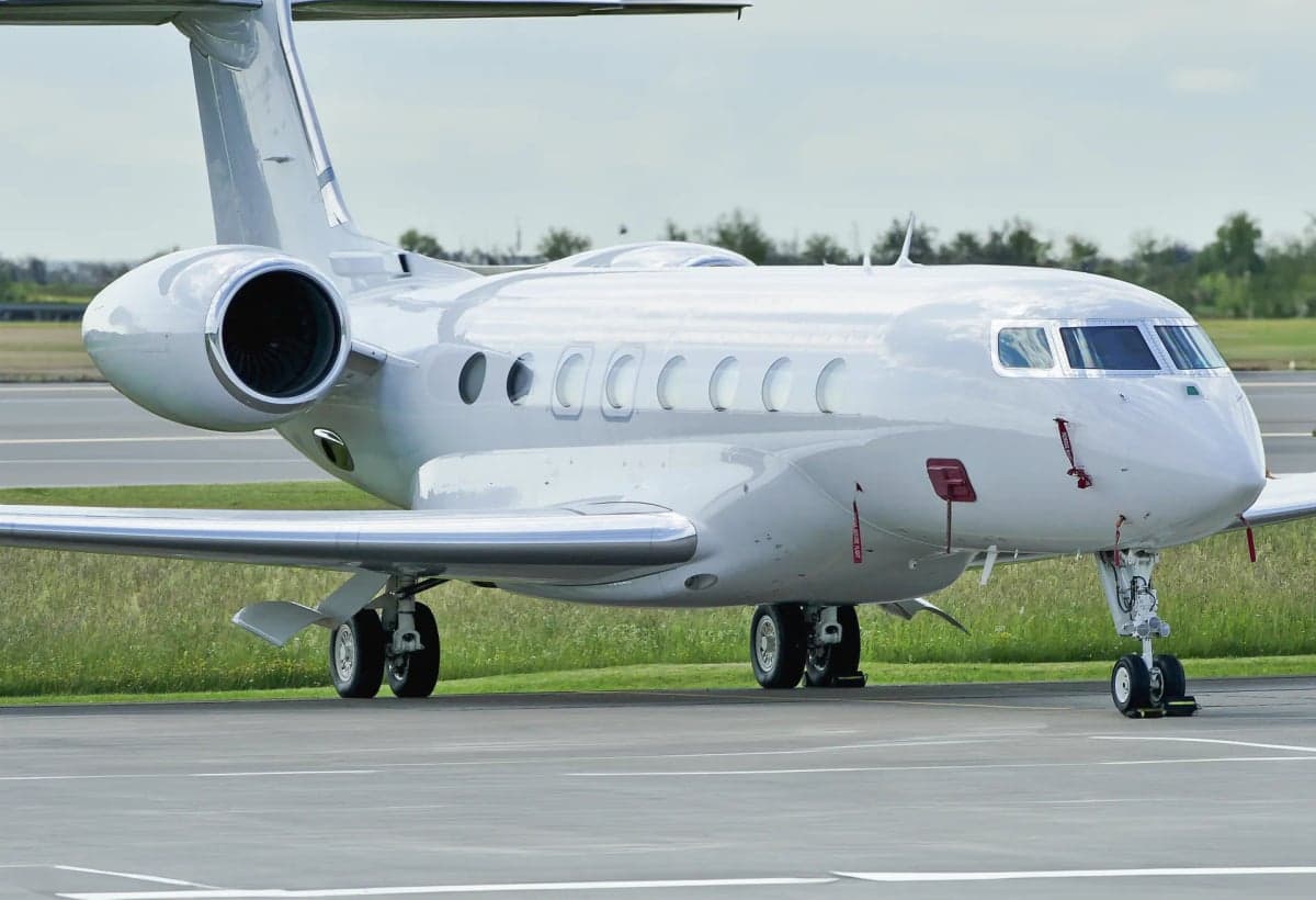 A white Gulfstream business jet is parked on the tarmac.