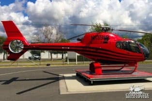 A red and black helicopter with the tail number N135MB on a platform outside.