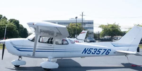 A white Cessna 172 aircraft with red and black stripes, registration N73868, parked on an tarmac.