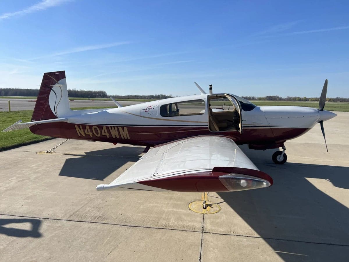 Mooney M20J with a white and maroon paint scheme parked on the tarmac.