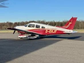 A Piper PA-28 Cherokee with registration D-EKJF, featuring a white and red paint scheme.
