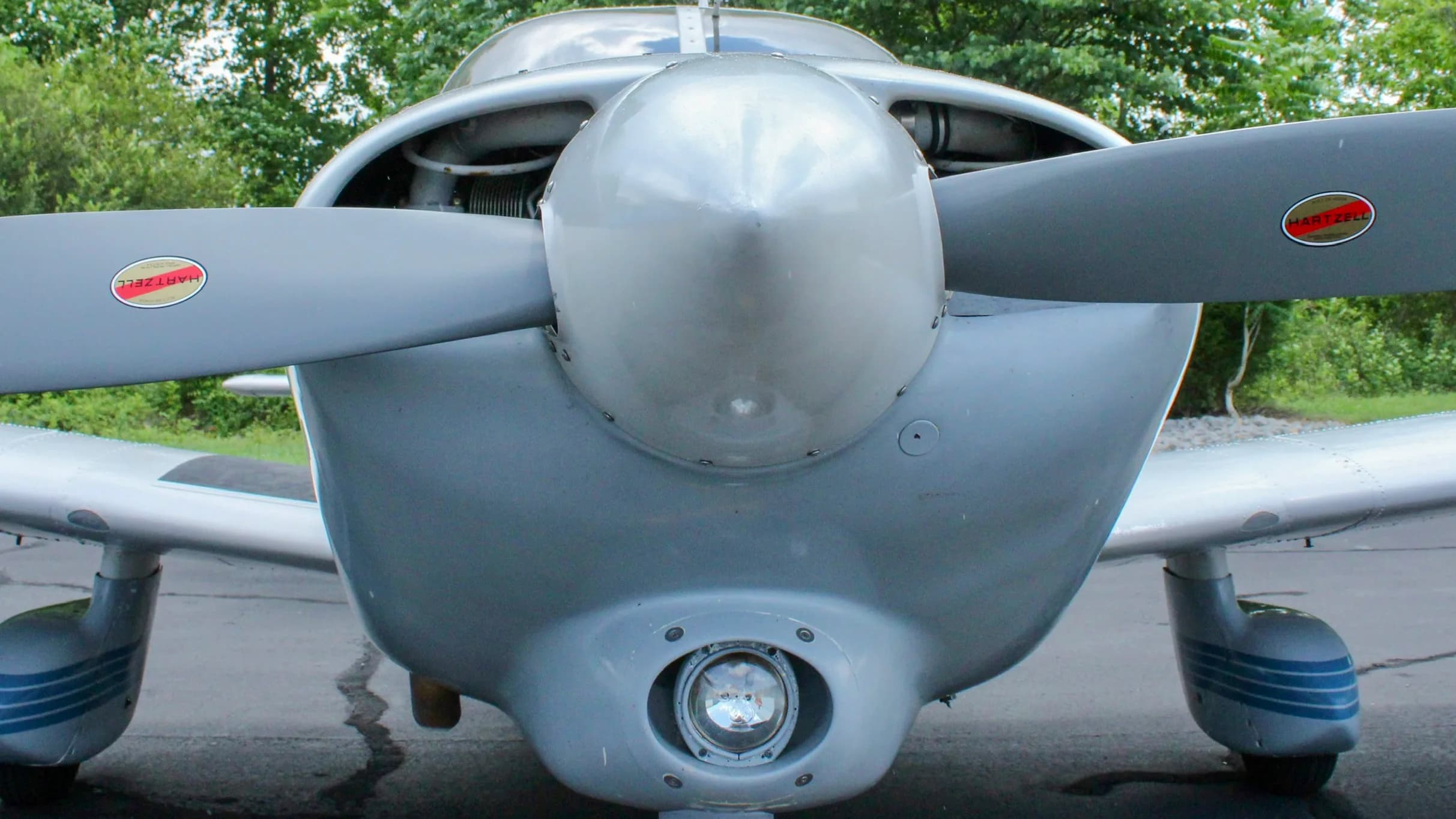 A close-up view of the propeller and nose of a white and blue Piper Cherokee aircraft.