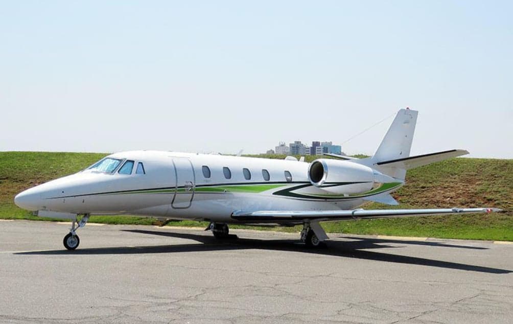 A Cessna Citation CJ3+ aircraft is parked on the tarmac with a white and green paint scheme.