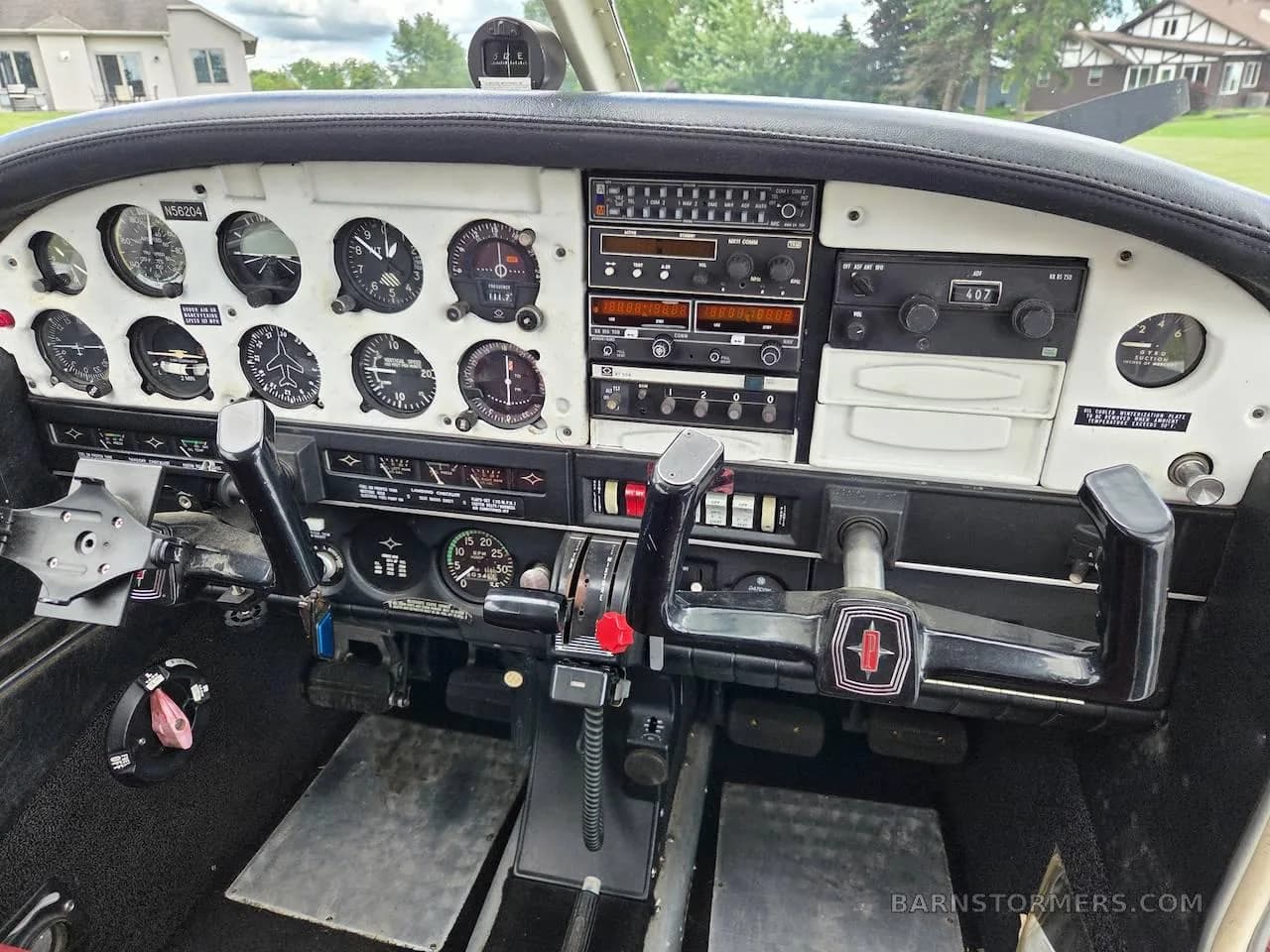 A detailed view of the instrument panel and controls in a Piper Cherokee cockpit, showing various gauges and radios.