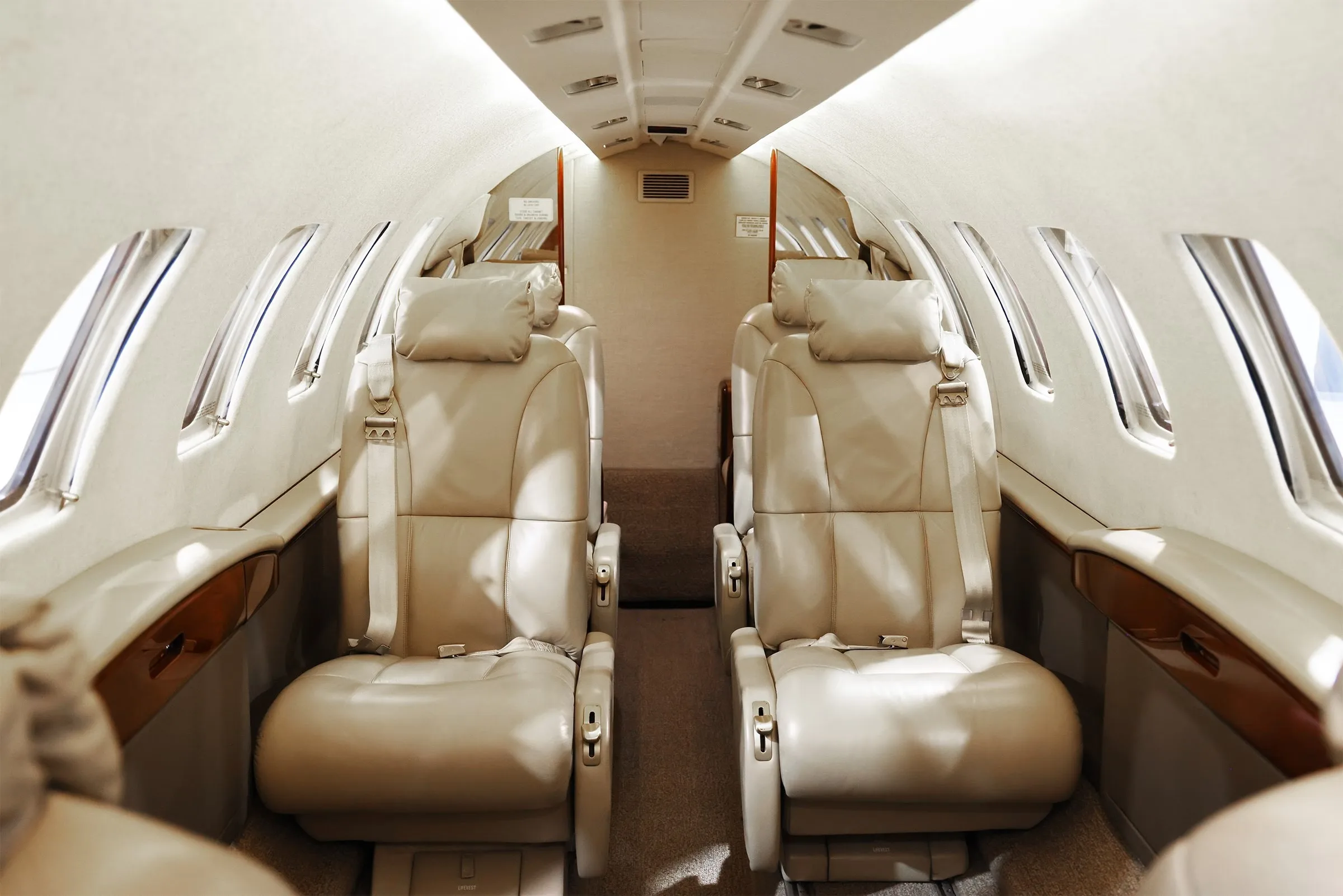 The beige leather cabin seats of the Cessna Citation CJ2+ interior, facing forward.