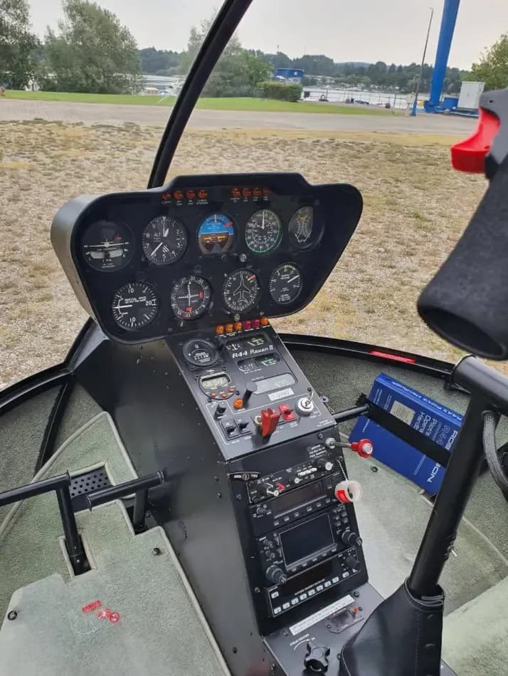 The cockpit of a Robinson R44 Raven II helicopter, showing the instrument panel and controls.