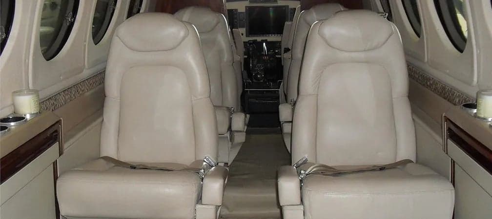 The aircraft's cabin features leather seats and side tables.