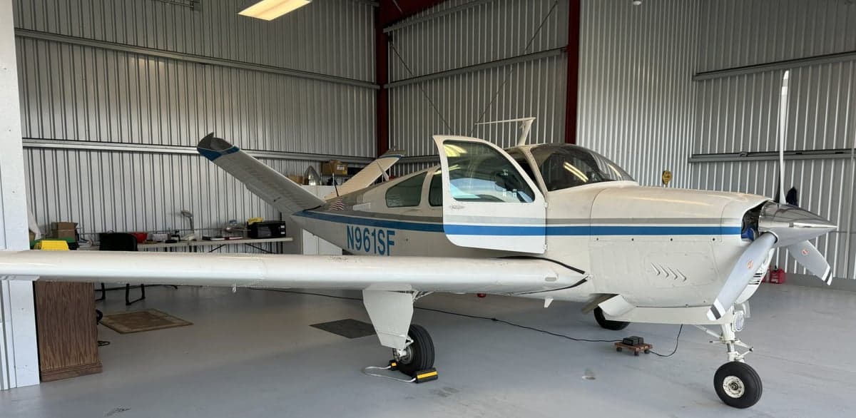 The Mooney M20K aircraft with registration N961SF is parked inside a hangar with its door open.