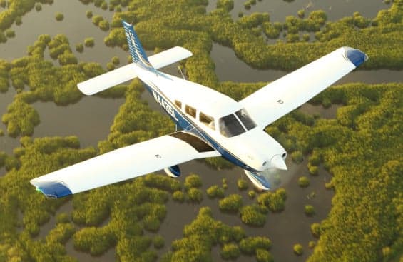 A Piper PA-28 Cherokee flying over a swamp.