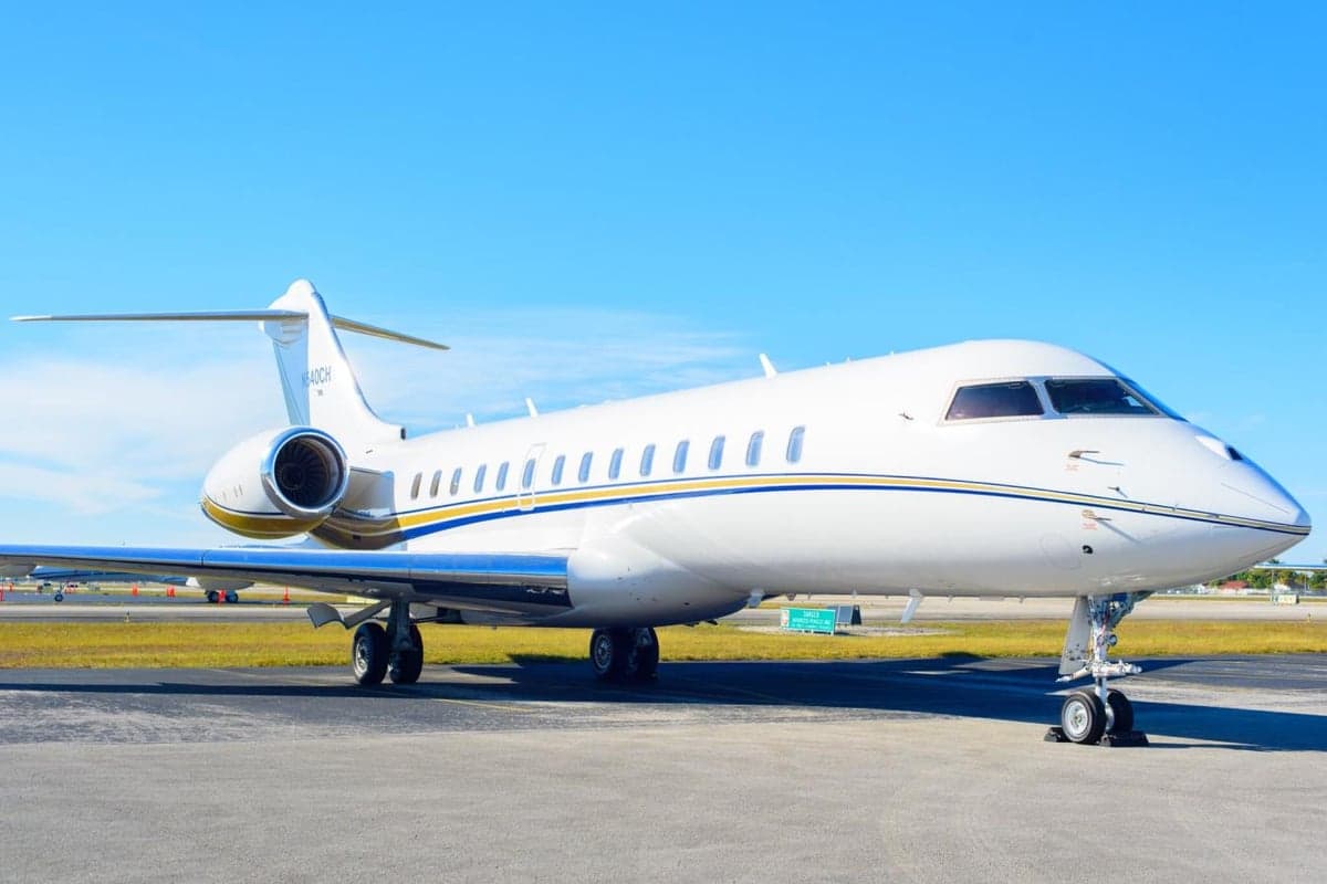 A white and gold Bombardier Global Express sits on the tarmac.