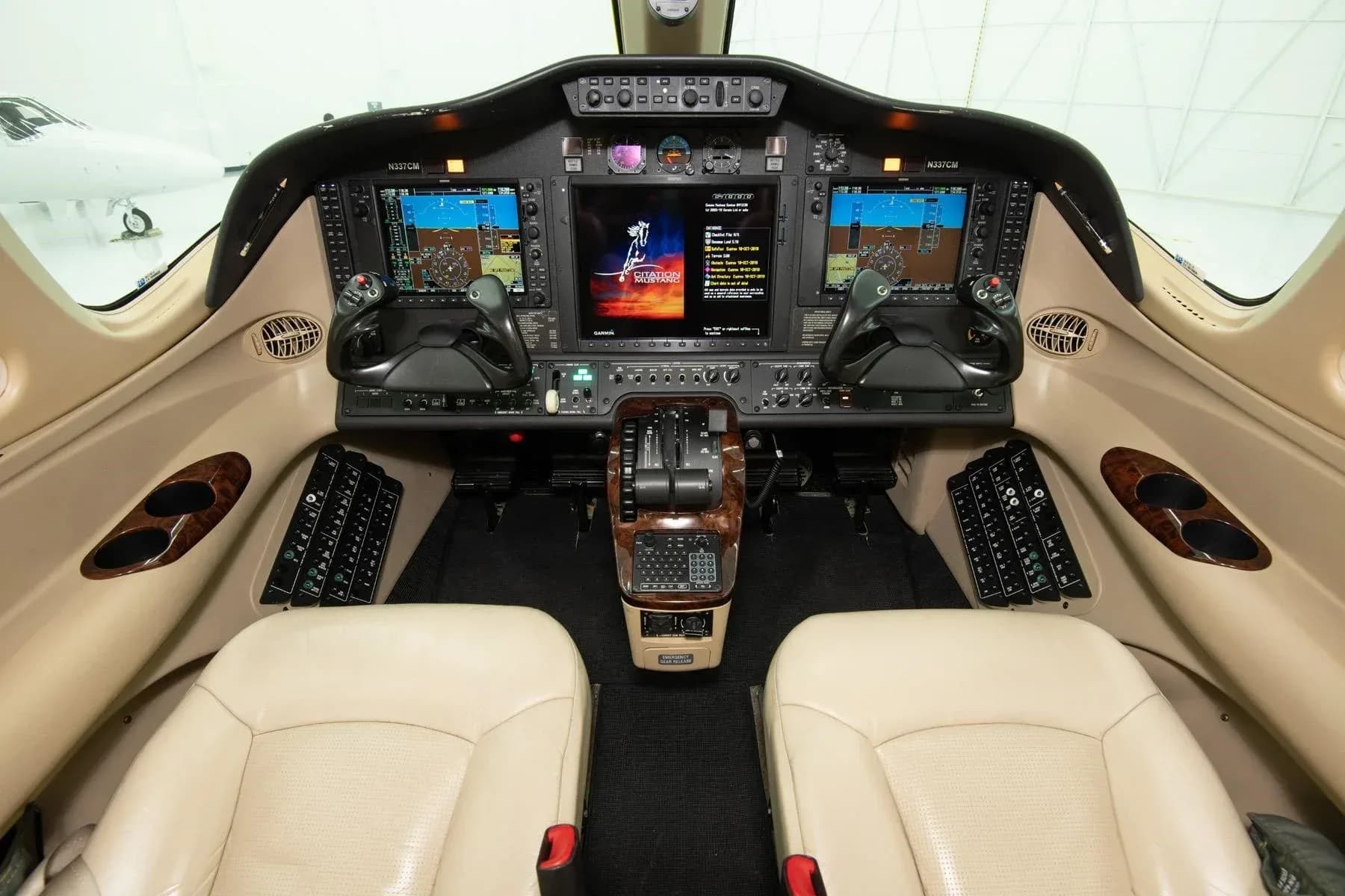 The cockpit of a Cessna Citation M2 with two beige pilot seats and a modern glass panel display.