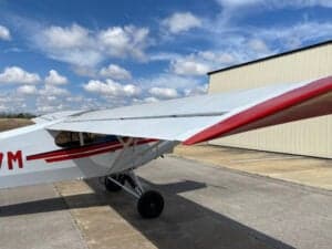 View of the wing and fuselage of a Piper Cub aircraft.