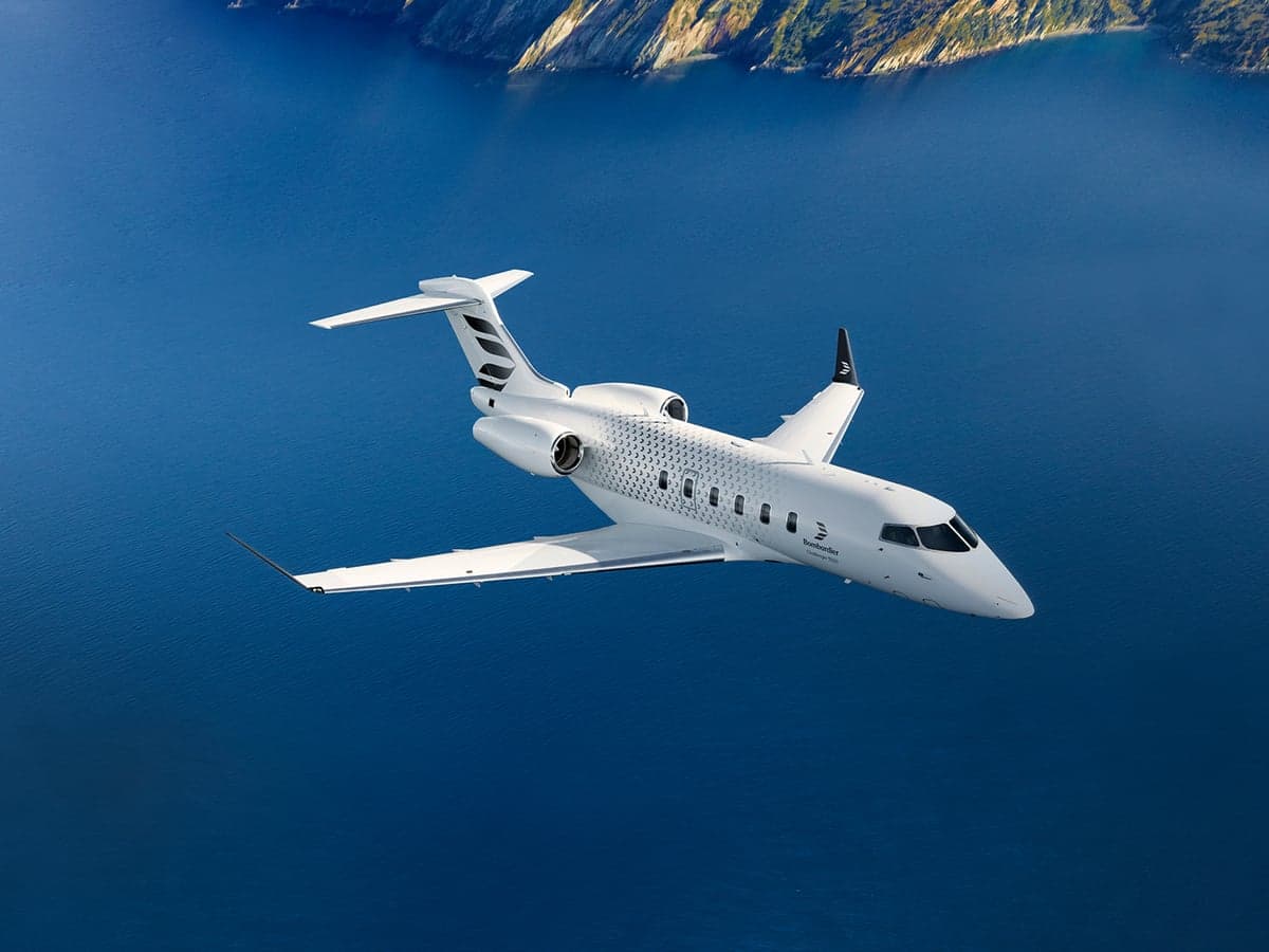 Stock photo of a white Bombardier Challenger in flight over water.