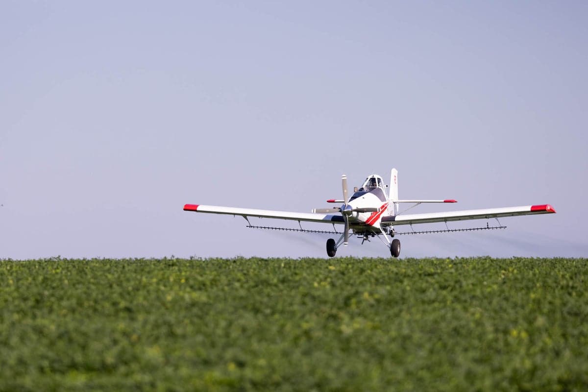 Crop duster aircraft flying over a field.