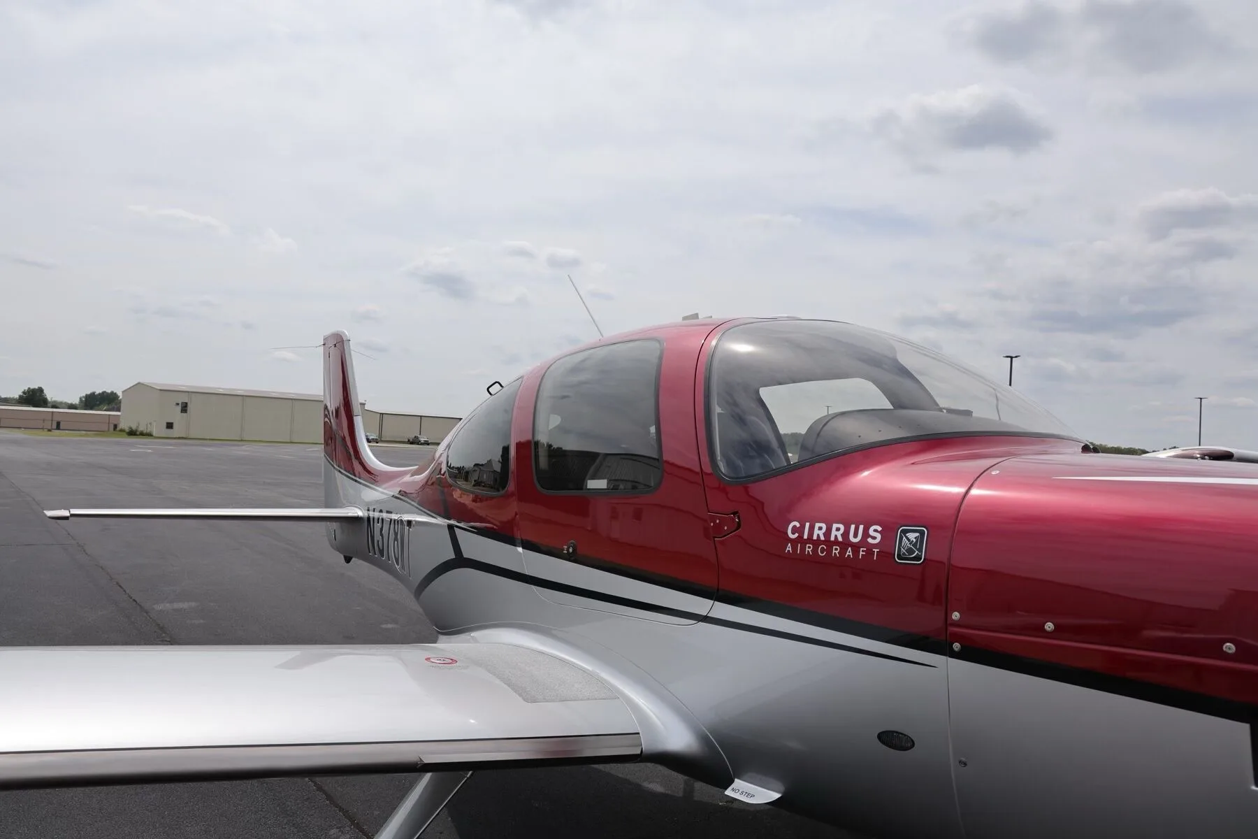 A close-up view of the red and silver cockpit and wing of the Cirrus SR22T aircraft.
