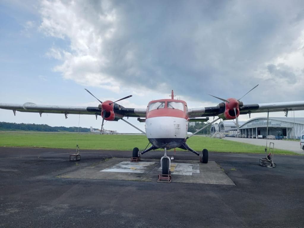 Front view of a red and white twin-engine aircraft on the tarmac.
