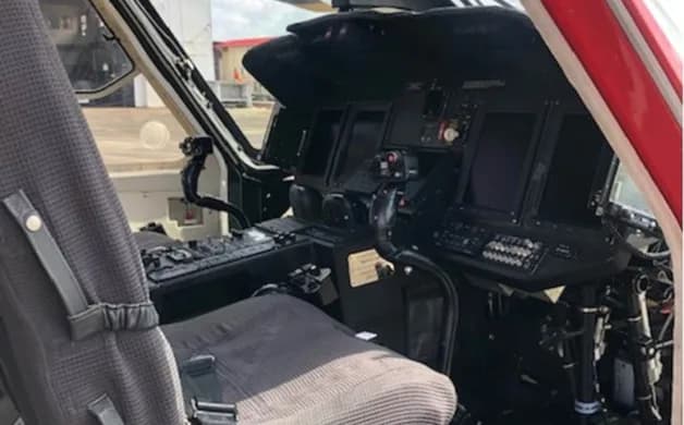 The modern glass cockpit of a helicopter, featuring multiple digital displays and flight controls.
