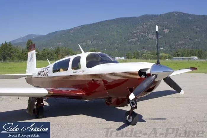 A Beechcraft Bonanza with a red and white paint scheme parked on the tarmac.