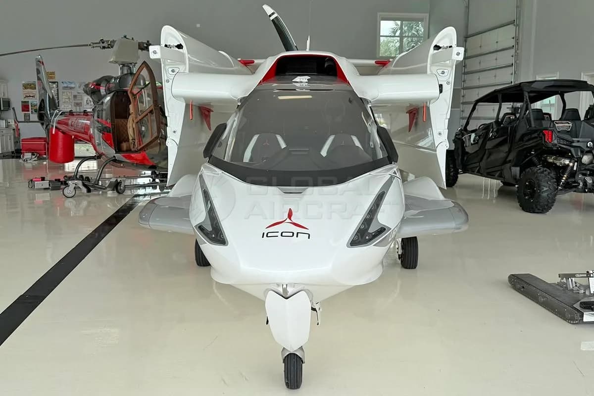 Front view of a white and red Icon A5 amphibious light sport aircraft with wings folded, inside a hangar.