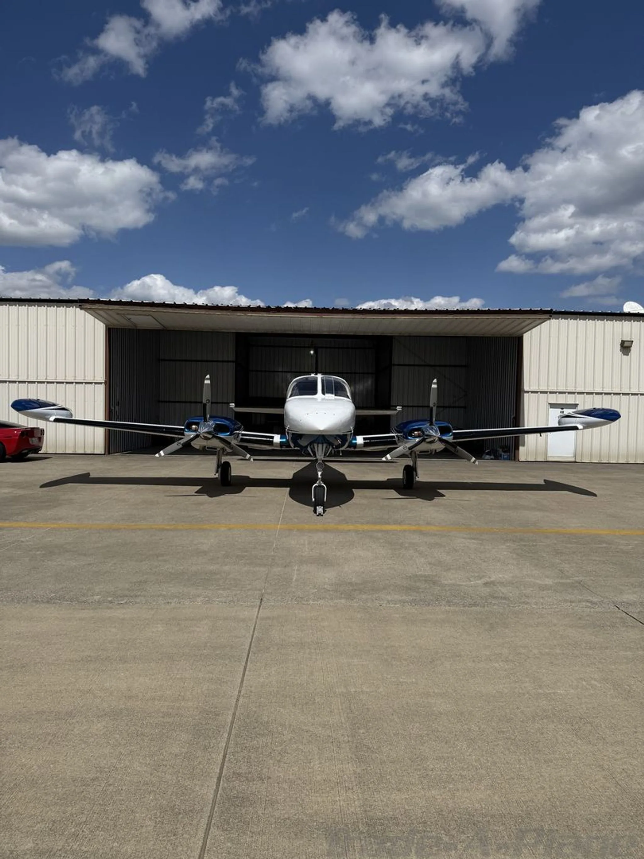 A head-on view of a white, blue, and gold Cessna 414 twin-engine aircraft parked on an apron.