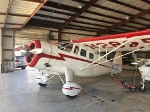 A Howard DGA-15P aircraft is parked inside a hangar.