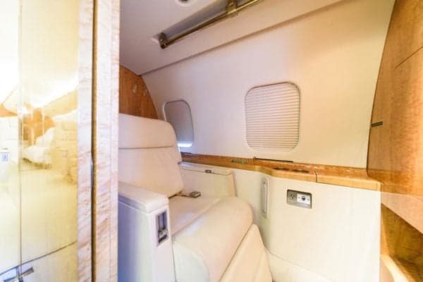 A single seat in the aircraft cabin with wood trim and a window.