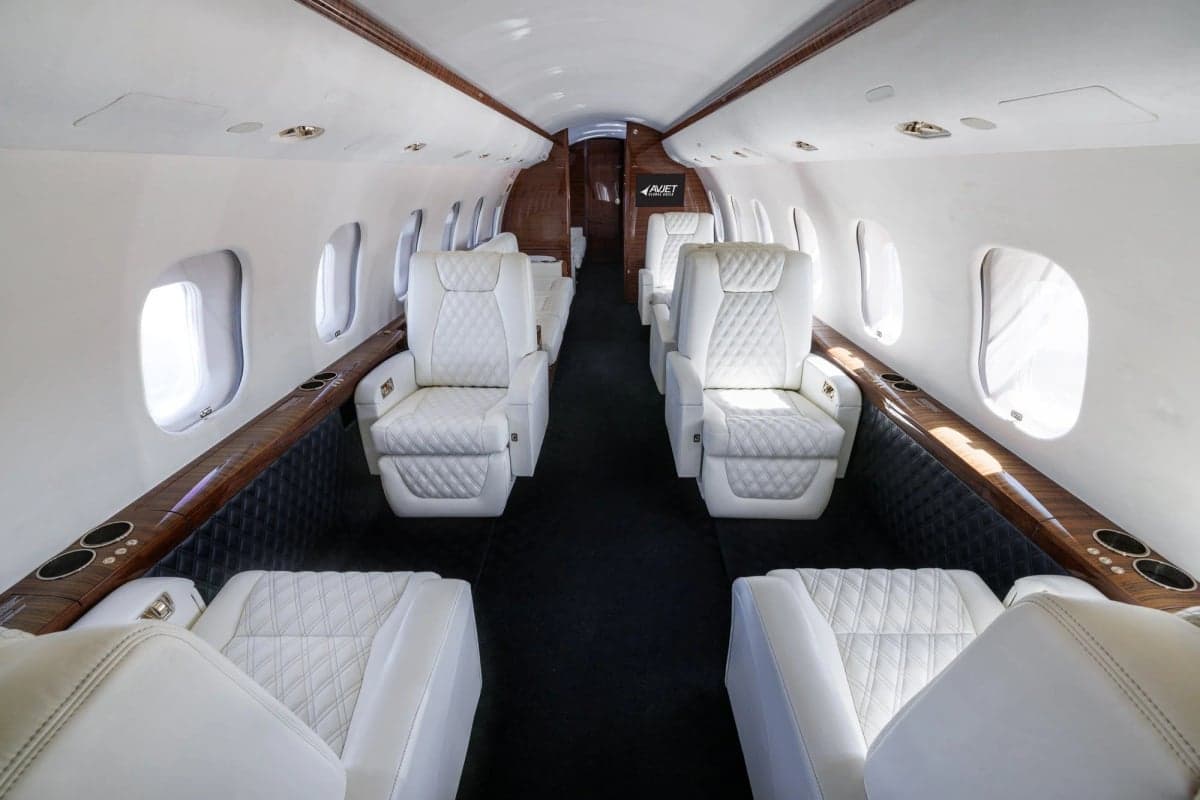 Interior view of a private jet cabin with white leather seats.