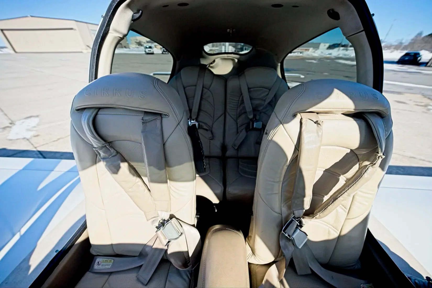 The light tan leather rear seats of a Cirrus SR22 aircraft cabin, viewed from the front.