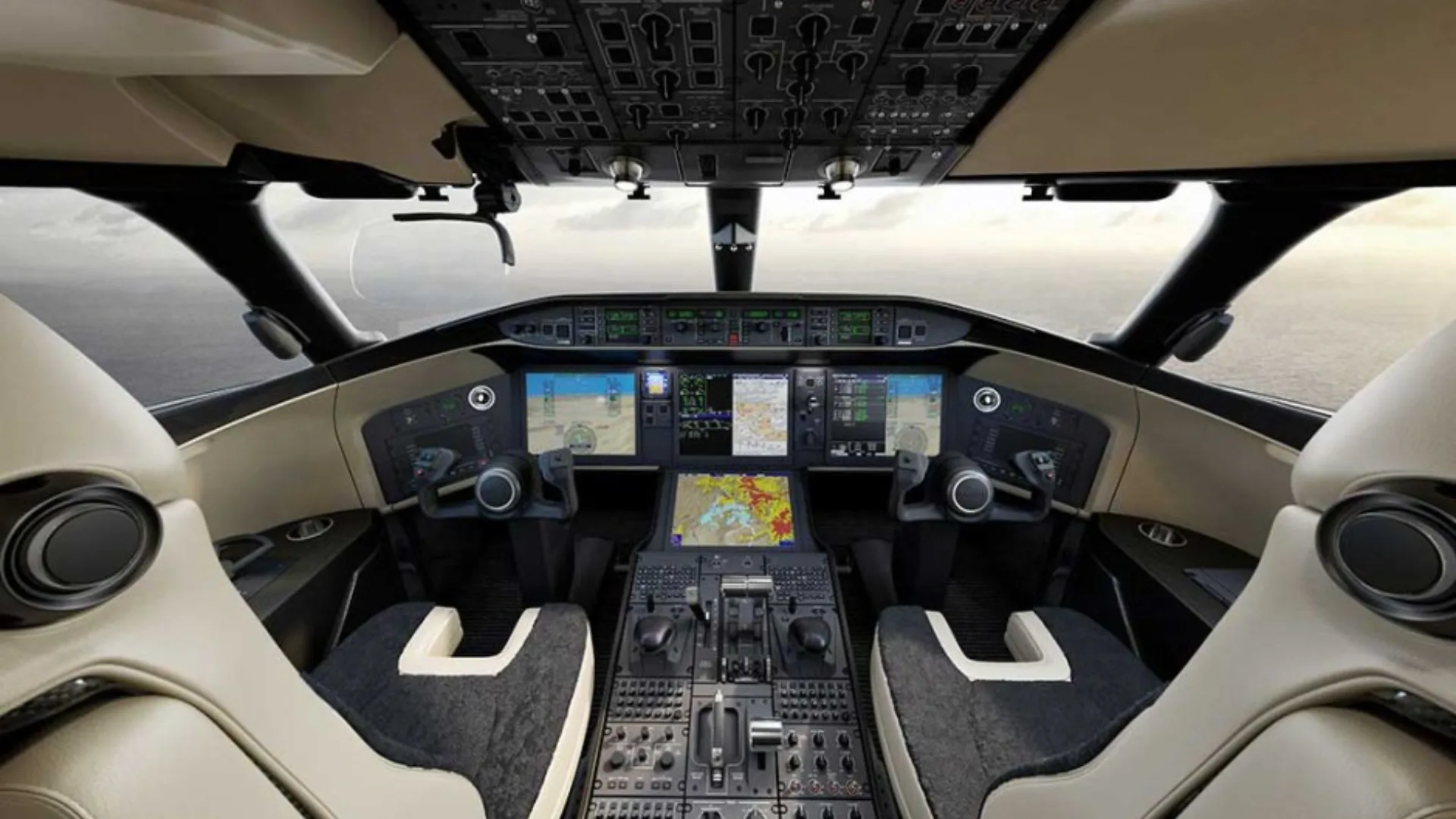 A modern aircraft cockpit with multiple digital displays, control yokes, and beige and black pilot seats.