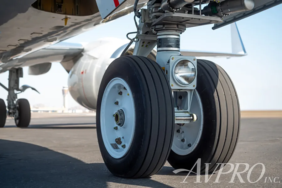 A close-up, low-angle view of the main landing gear wheels of a Boeing 737 business jet on the tarmac.