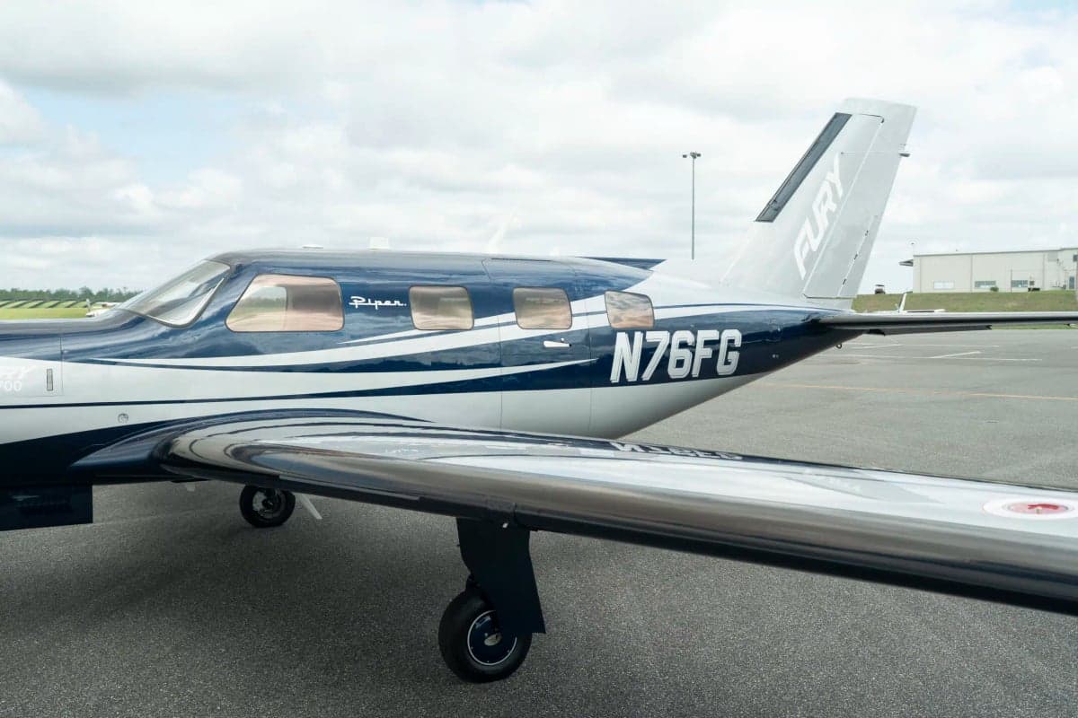 A close-up view of the tail and right wing of the Piper M700 Fury aircraft, showing the N-number N76FG and 'Fury' on the tail.