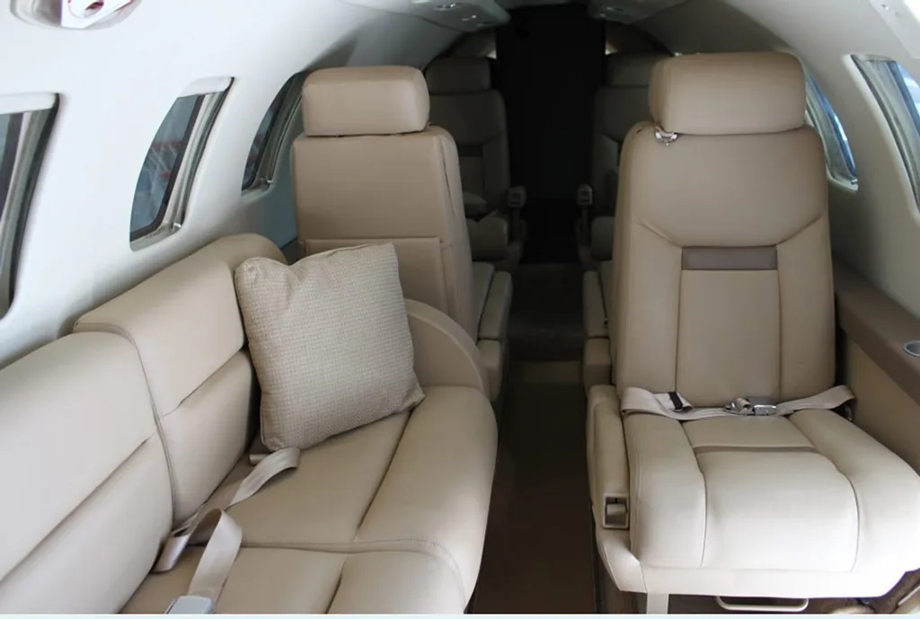 The aircraft cabin interior with beige leather seats and a side couch.