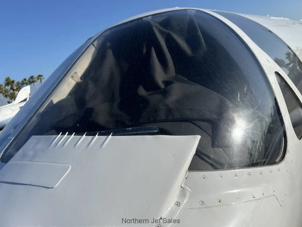 Close up of the cockpit windshield of a white jet.