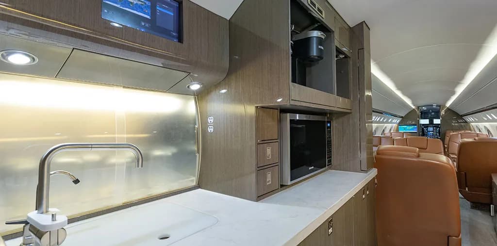 The aircraft galley with a sink, microwave, coffee maker, and storage cabinets.