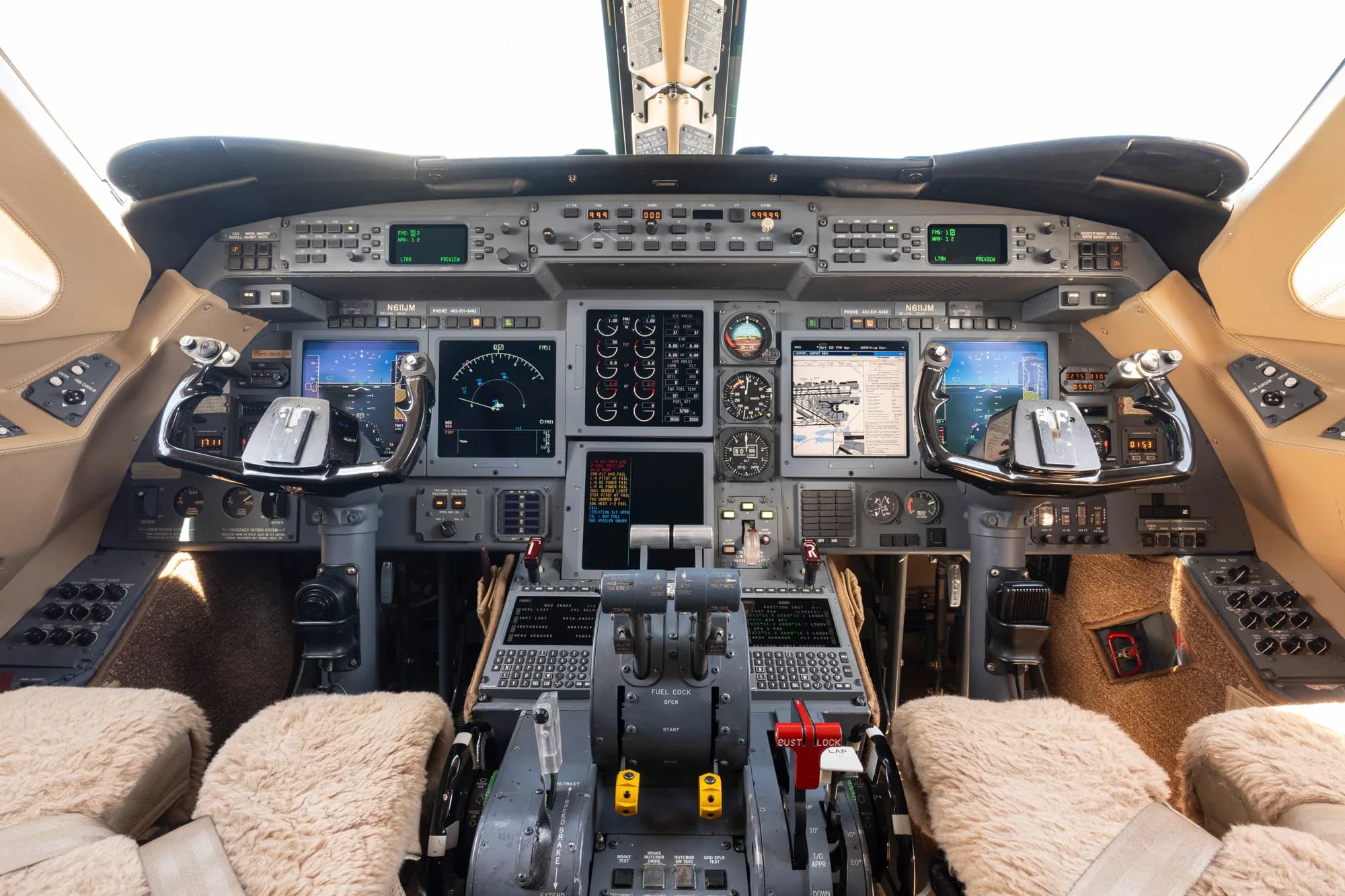 The cockpit of a business jet with multiple display screens and controls.