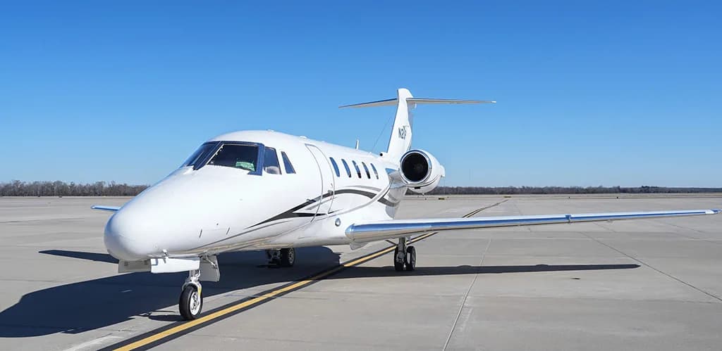 A white Cessna Citation business jet with black and grey stripes, registration N2UP, parked on an airfield from a front-quarter view.