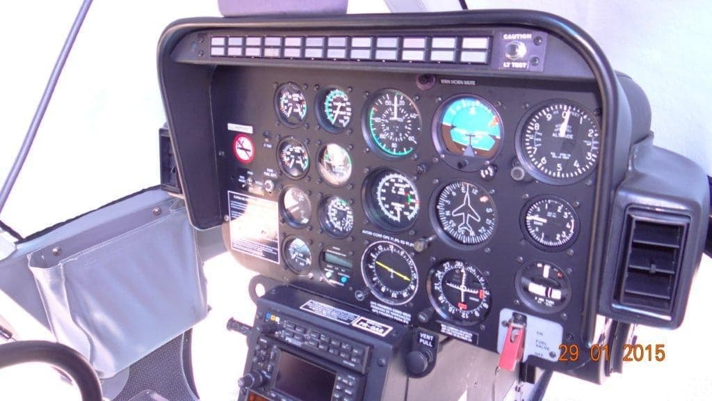 The instrument panel of a helicopter, featuring multiple analog gauges and a radio stack.