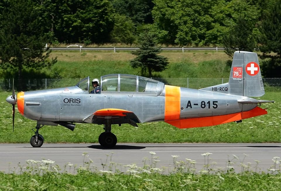 Pilatus PC-7 in flight with orange and silver paint scheme.